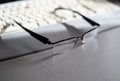 Closeup of laptop, glasses, coffee cup and other items on white desktop with blurry city Royalty Free Stock Photo