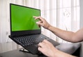 Closeup of a laptop with green screen space and a person's fingers tapping on the screen