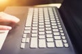 Closeup of a laptop keyboard with man's hand touching mouse pad.