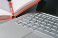 Closeup laptop keyboard and opened notebook