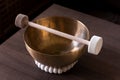 A closeup of a large himalayan bowl, also called a singing bowl, with a mallet lying on top of it to make a relaxing sound. The