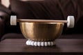 A closeup of a large himalayan bowl, also called a singing bowl, with a mallet lying on top of it to make a relaxing sound. The