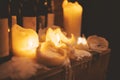 Closeup of large light color burning candles and dark glass wine bottles Royalty Free Stock Photo