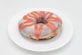 Large White and Red Glazed Donut on a White Plate with a White Background Royalty Free Stock Photo