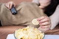 lazy woman eating potato chips lay down on couch and watching tv Royalty Free Stock Photo