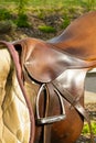 Closeup leather cowboy saddles hanging on the railing