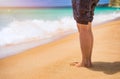 Closeup on leg of young woman standing on sea shore. Woman legs and feet walking on the sand of the beach with the sea water in Royalty Free Stock Photo