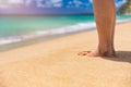 Closeup on leg of young woman standing on sea shore. Woman legs and feet walking on the sand of the beach with the sea water in Royalty Free Stock Photo