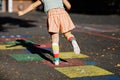 Closeup of leggs of little toddler girl playing hopscotch game drawn with colorful chalks on asphalt. Little active