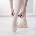 Closeup legs of ballerina puts on pointe ballet shoes