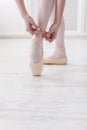 Closeup legs of ballerina puts on pointe ballet shoes