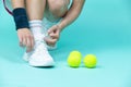 Closeup on Legs of Caucasian Female Tennis Player Grasping Tennis Sneakers Shoelaces  Over Blue Royalty Free Stock Photo