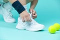 Closeup on Legs of Caucasian Female Tennis Player Grasping Tennis Sneakers Shoelaces  Over Blue Royalty Free Stock Photo