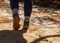 Closeup of the legs of a hiker wearing dirty shoes walking on a dirt trail