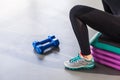 Closeup legs, sneakers,step platform and dumbbells. Woman sit