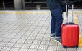 Closeup legs of tourist man with small red luggage waiting for the Japan subway to the airport