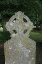 Closeup of lichen-covered Celtic Cross grave stone in a European cemetery