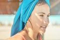 Closeup lifestyle portrait of smiling teen girl with green eyes at the beach with blue towel on the head. Summer