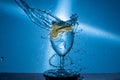 Closeup of lime slices dropping into a glass of water against a blue background Royalty Free Stock Photo