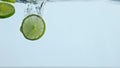 Closeup lime slices underwater on white background. Citrus falling under water. Royalty Free Stock Photo