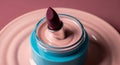 A closeup of a lipstick and cream in a jar on a plate with a pink background Royalty Free Stock Photo