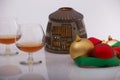Closeup of liquor glass with Christmas ornaments and craft lamp with candle, white backgrounds and reflections