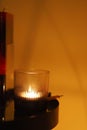 Closeup of a lit candle on the side of the table illuminating the dark room Royalty Free Stock Photo