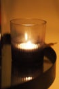 Closeup of a lit candle on a table illuminating the dark room Royalty Free Stock Photo