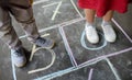 Closeup of little boy and girl legs and hop scotch drawn on asphalt. Child playing hopscotch game on playground outdoors on a Royalty Free Stock Photo