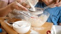 Closeup of little boy with mother sifting flour with sieve. Children cooking with parents, little chef, family having Royalty Free Stock Photo