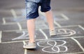 Closeup of little boy`s legs and hopscotch drawn on asphalt