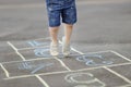 Closeup of little boy`s legs and hopscotch drawn on asphalt