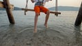 Closeup of little boy swinging on the sea beach and touching ocean waves with feet. Holiday, summer vacation and tourism Royalty Free Stock Photo