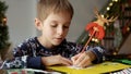 Closeup of little boy thinking of his wishes while writing a letter to Santa on Christmas Royalty Free Stock Photo