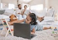 Closeup of a little cute girl using a laptop and wireless headphones while laying on the floor in the lounge. Hispanic Royalty Free Stock Photo