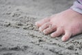 Closeup little feet of child standing on sand at edge of beach. During summer or spring season. Sensory development concept. Royalty Free Stock Photo