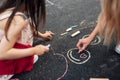 Closeup of little girl drawing with colorful chalks on the playground. Child playing with her mom the summer`s games outside. Kid Royalty Free Stock Photo