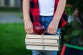 Closeup Little girl hands are holding a stack of books and red apple on them. Back to school. Education concept. Child carrying a