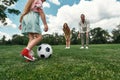 Closeup of little girl kicking the ball while parents watching. Young family playing football on the grass field in the Royalty Free Stock Photo