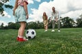 Closeup of little girl ready for kicking the ball. Young family playing football on the grass field in the park on a Royalty Free Stock Photo