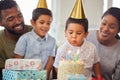 Closeup of a little mixed race boy blowing the candles on a cake at a birthday party with his little brother and parents Royalty Free Stock Photo