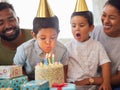 Closeup of a little mixed race boy blowing the candles on a cake at a birthday party with his little brother and parents Royalty Free Stock Photo