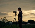 Closeup of a long hair photographer filming on a tripod at sunset