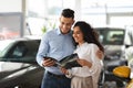 Closeup of loving arab couple checking booklet in car salon