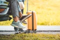 Closeup lower body of group of friends relaxing on SUV car trunk with yellow trolly luggage along road trip with mountain hill Royalty Free Stock Photo