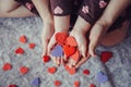 Macro of child with adult parent hands palms holding a bunch of small red and purple paper foam hearts Royalty Free Stock Photo