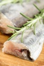 Closeup macro fresh raw hake fish with rosemary branches on the wooden board Royalty Free Stock Photo