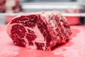 Closeup macro pieces ribeye marbled beef steak on red plastic cutting board on metal table in restaurant kitchen. Concept packing