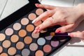 Closeup make-up visagiste hands, professional decorative cosmetic, palette, set of eye shadows and brush on white wooden Royalty Free Stock Photo