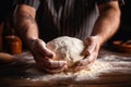 closeup of a male chef\'s hands kneading dough on a wooden table